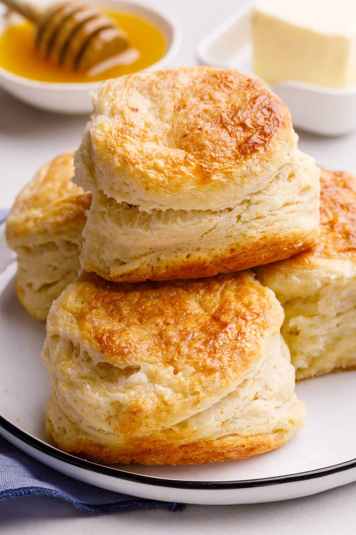 close up image of stacked buttermilk biscuits served on a white round plate