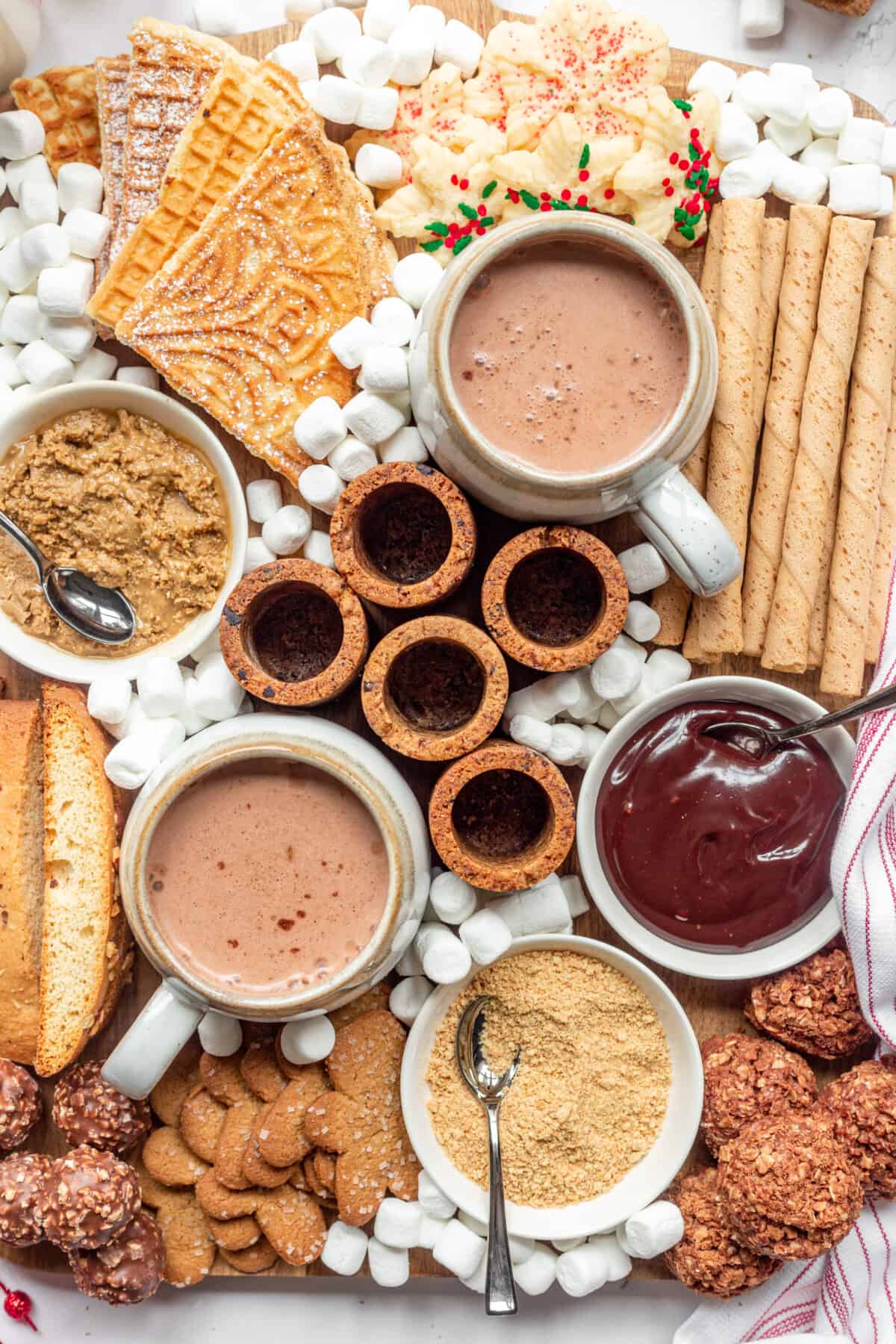 A farmhouse chic hot chocolate bar board with cookies, spreads, and hot chocolate. 