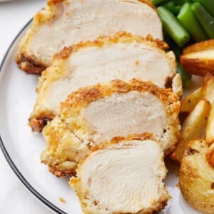 Crispy almond chicken pieces on a plate with potatoes and green beans.