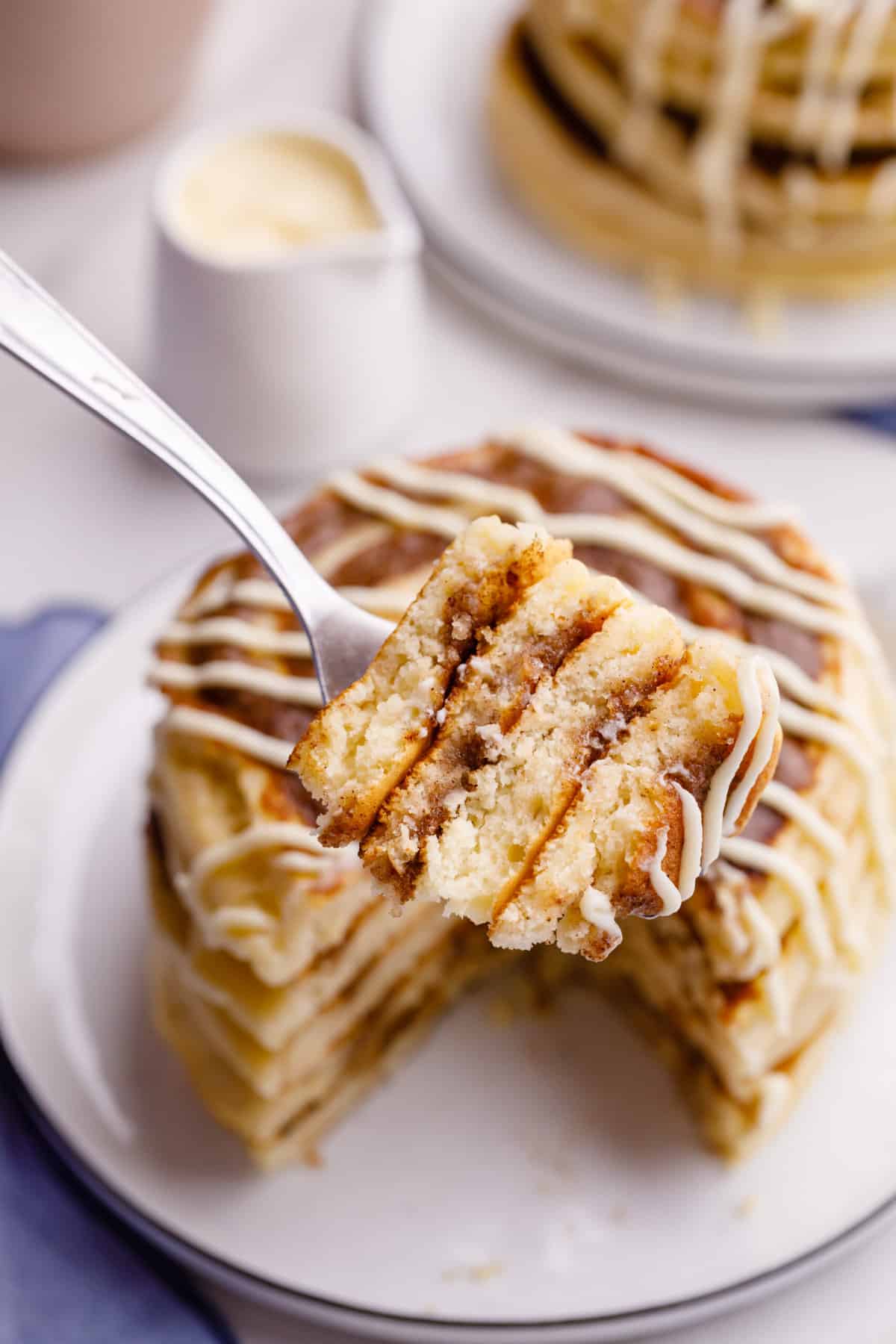 close up image of a bite of cinnamon roll pancakes showing the layers and cross section