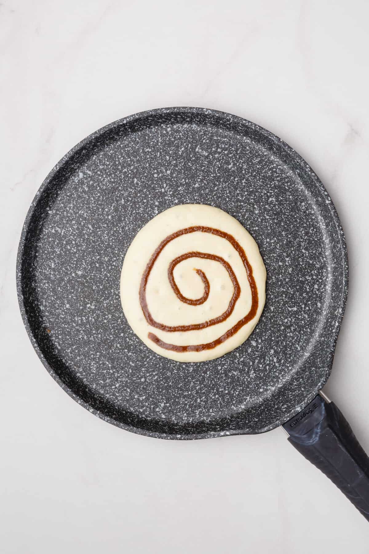 Cinnamon swirl pancake cooking in skillet.