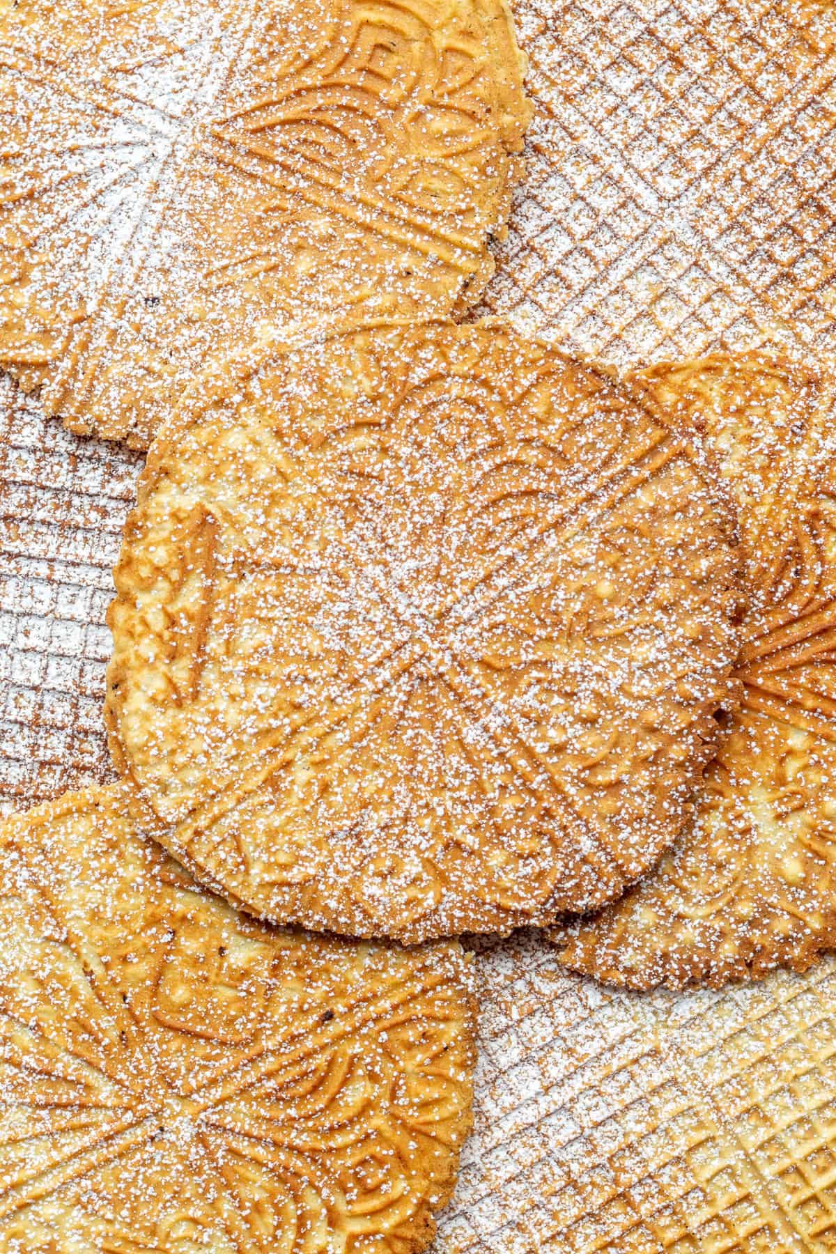 top down image of pizzelles with powdered sugar.