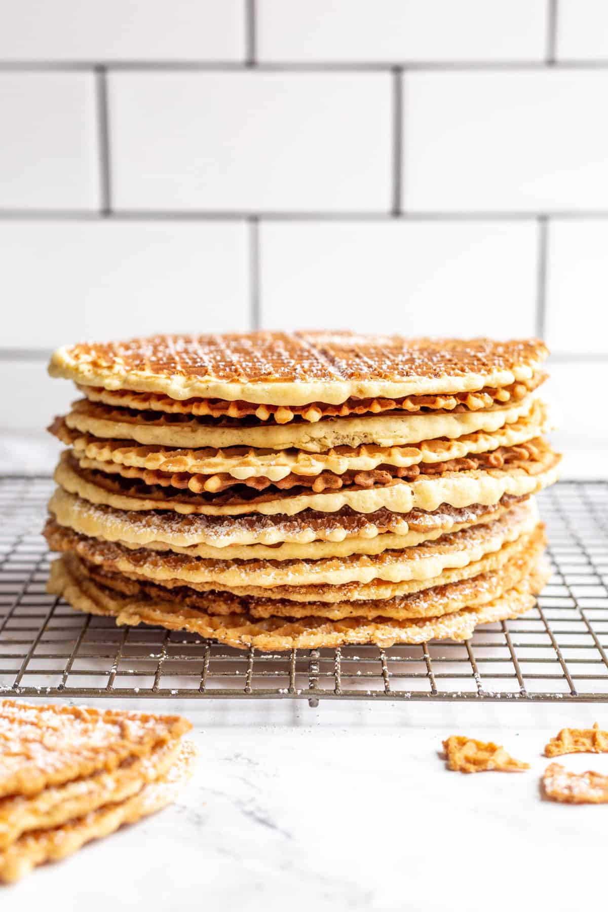 stack of made pizzelles dusted with powdered sugar.