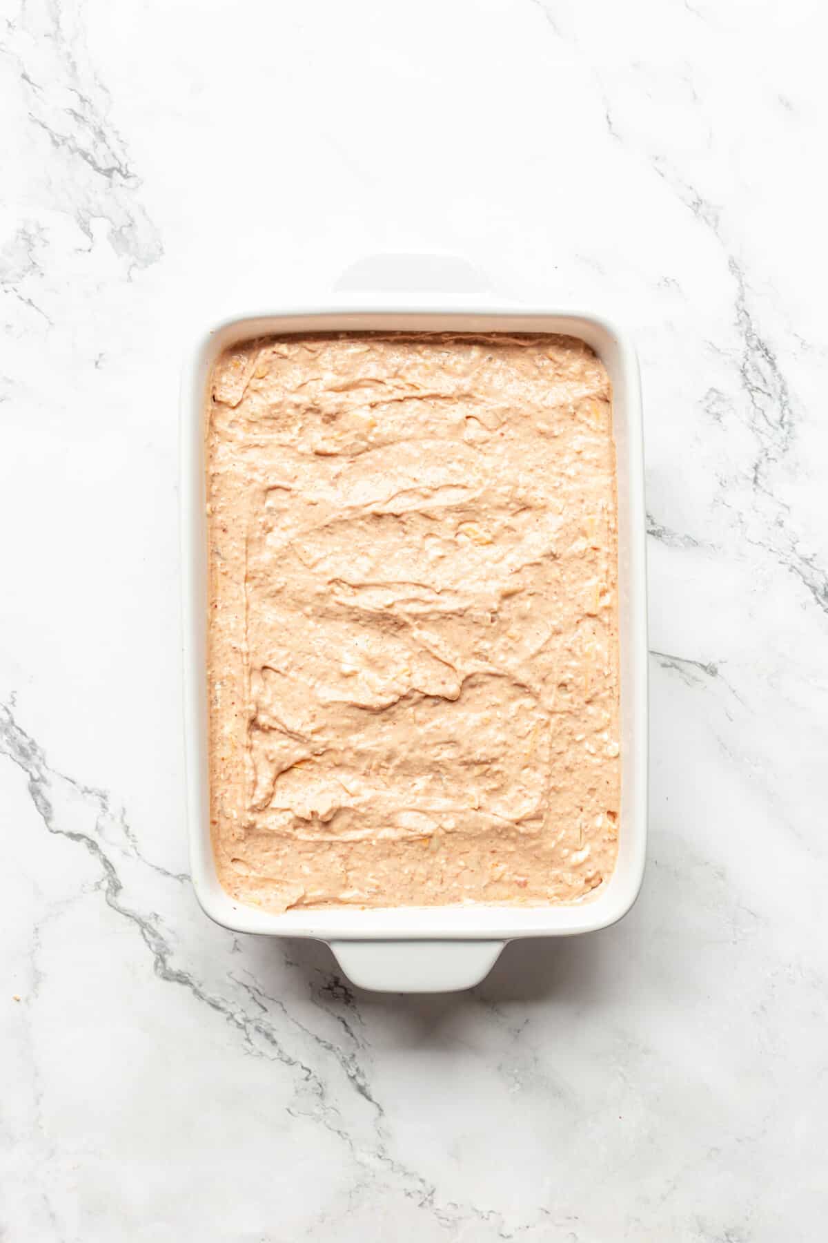 Refried bean dip with cream cheese in baking dish.