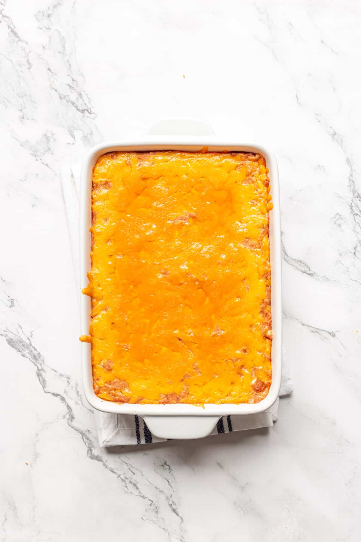 Cheesy refried bean dip in baking dish.