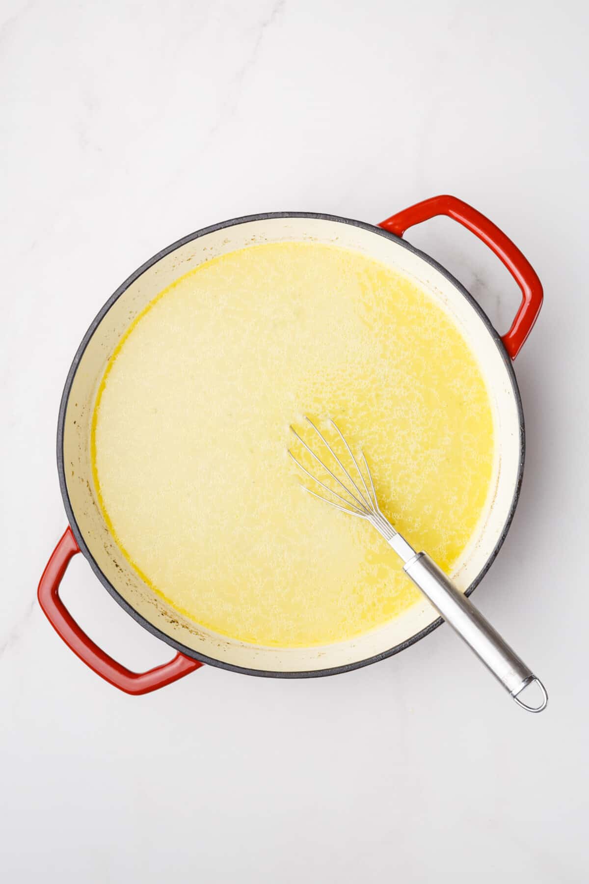 Cream sauce in Dutch oven with whisk.
