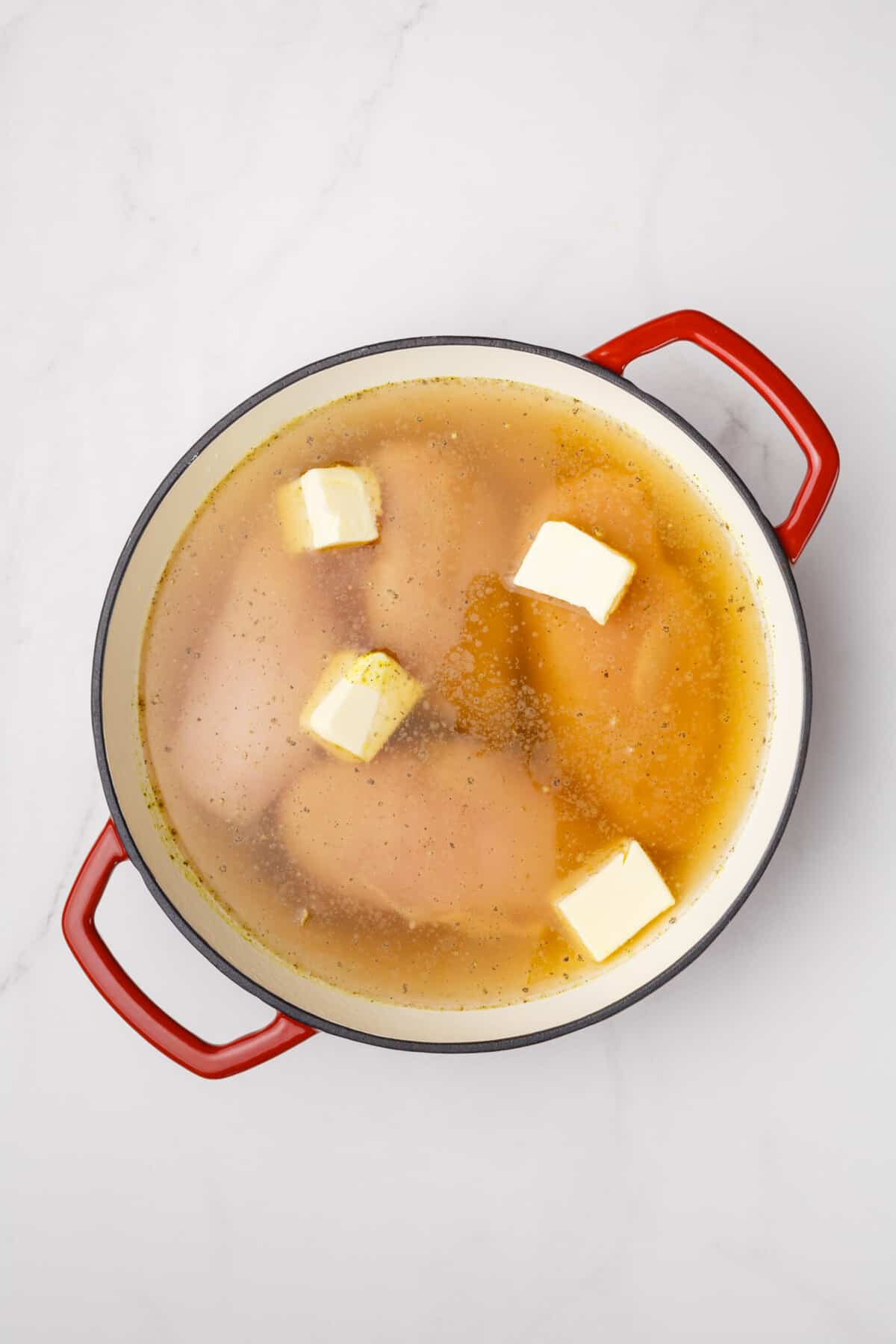 Chicken cooking in broth with butter.