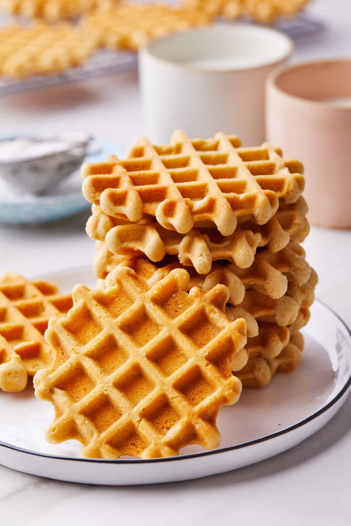 stack of waffle cookies sitting on a white round plate