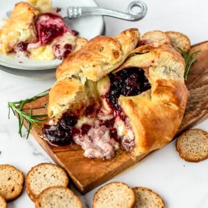 Baked brie on a cutting board surrounded by crackers.