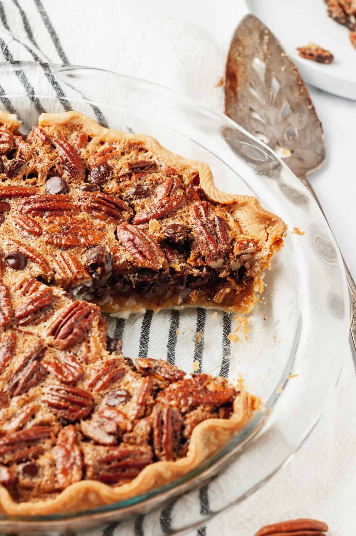 Close up of chocolate pecan pie cross section in a glass pie dish.