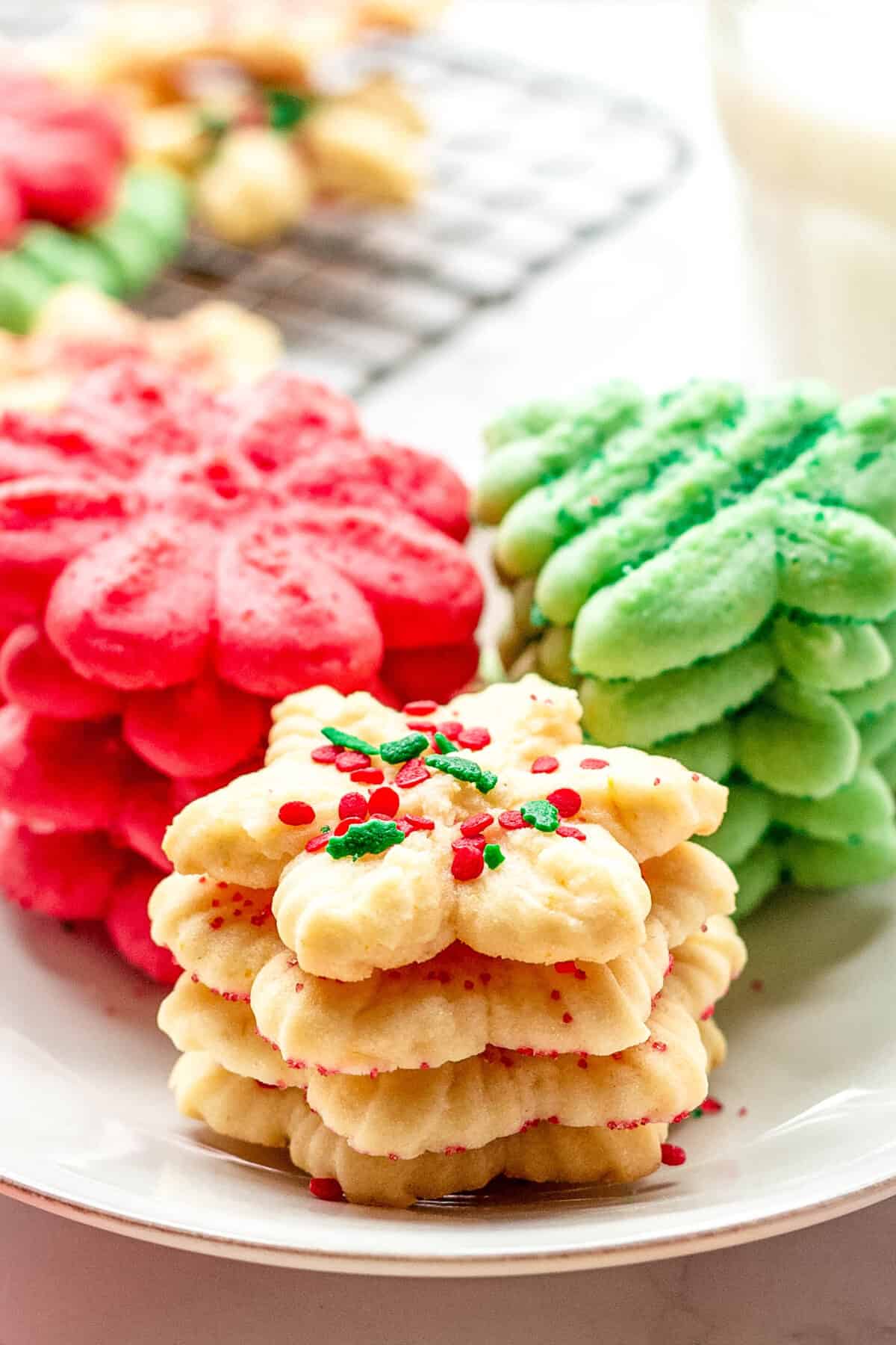 Stacks of cream cheese spritz cookies - white snowflakes, red flowers, and green Christmas trees. 