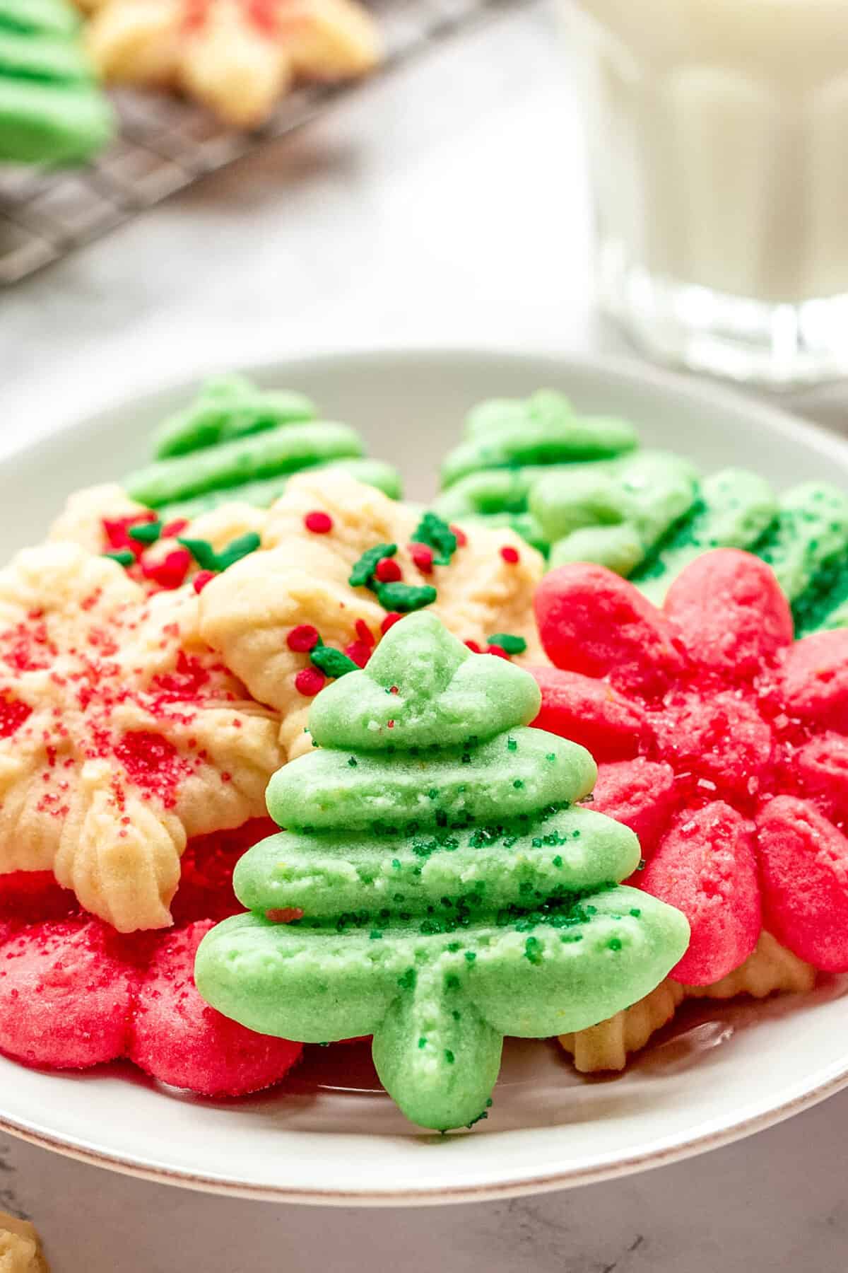 A plate of red, green, and white cream cheese spritz cookies in Christmas shapes. 