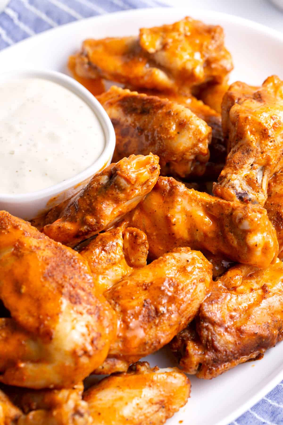 close up image of crockpot buffalo chicken wings served on a large white plate with a side of ranch
