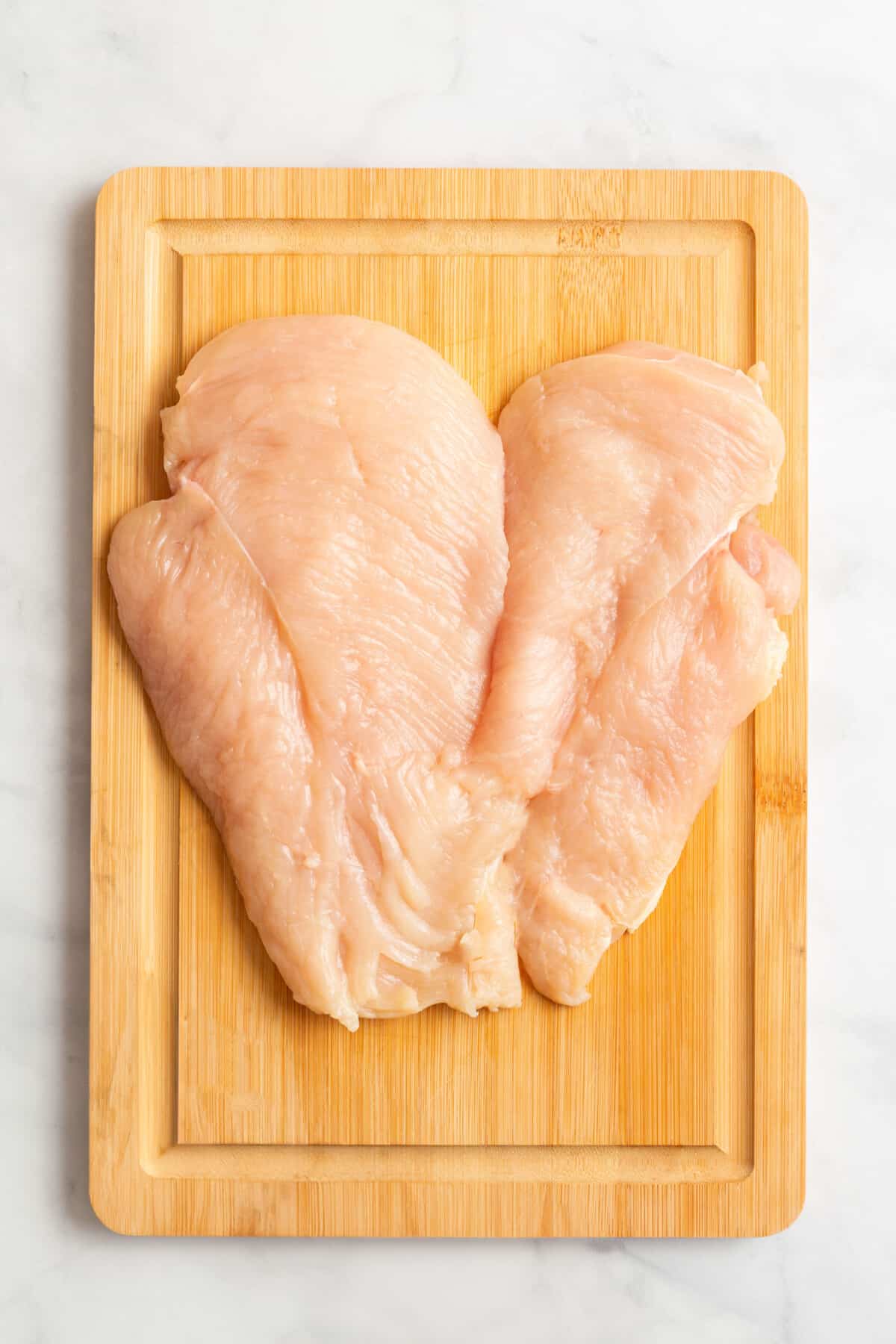 Butterflied chicken breast on a cutting board.