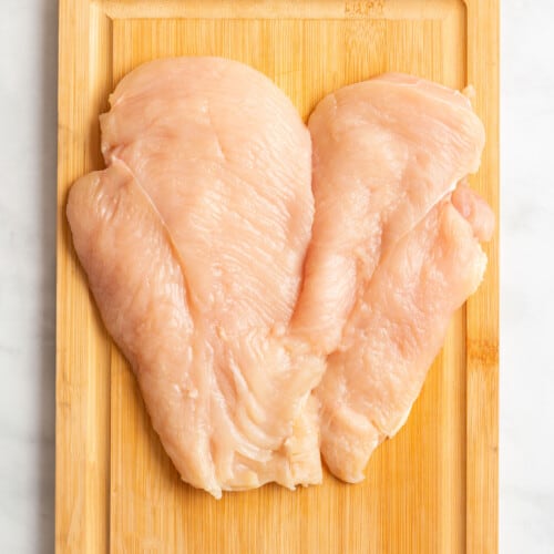 Butterflied chicken breast on a cutting board.
