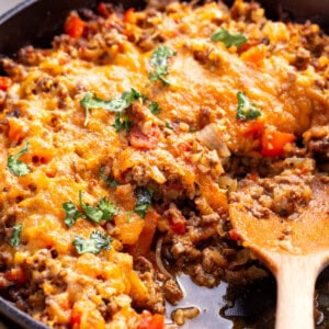 A skillet full of Mexican cauliflower rice with a wooden spoon.