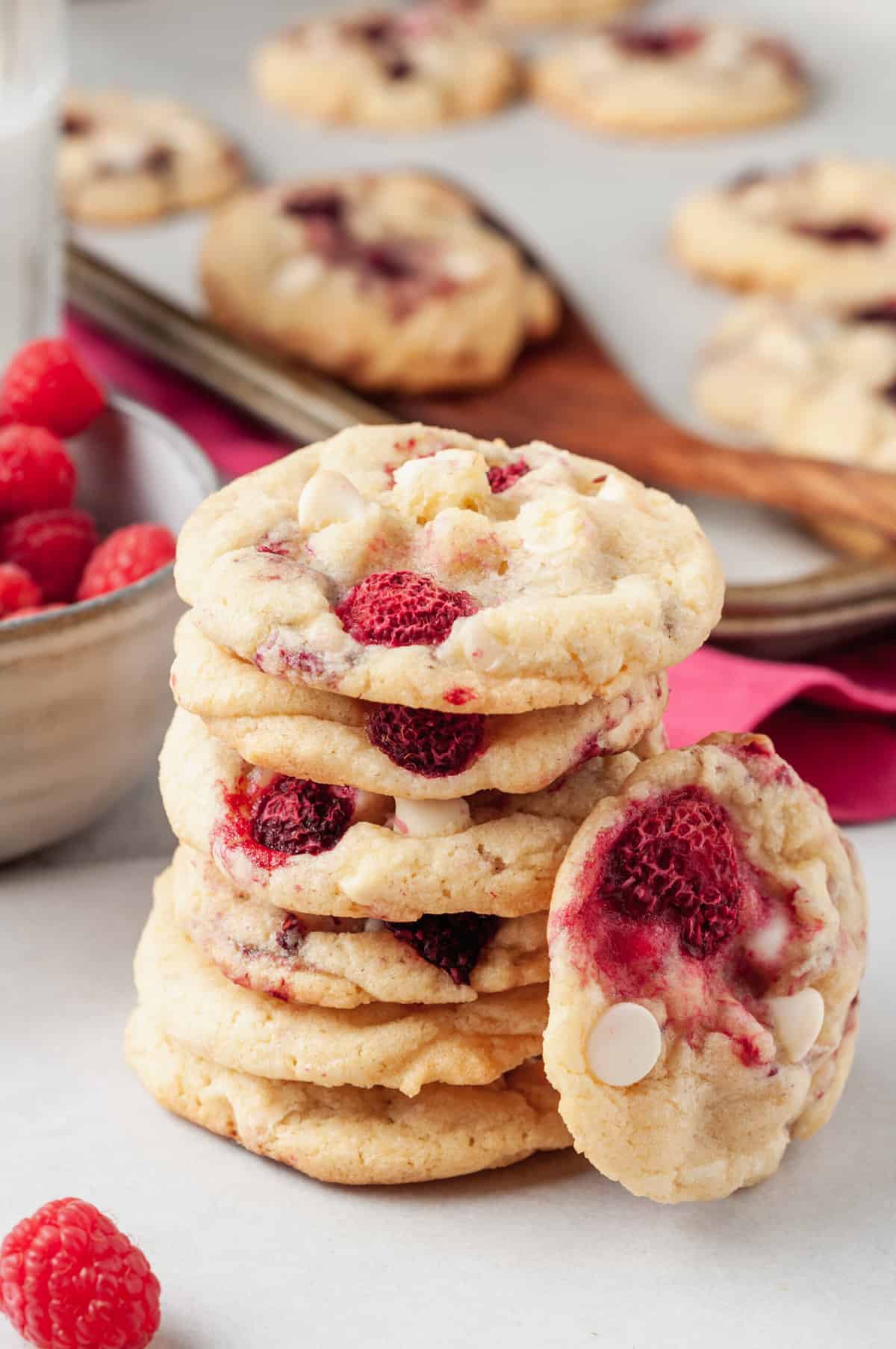 close up image of a stack of six raspberry cookies with one cooking leaning against the stack of cookies