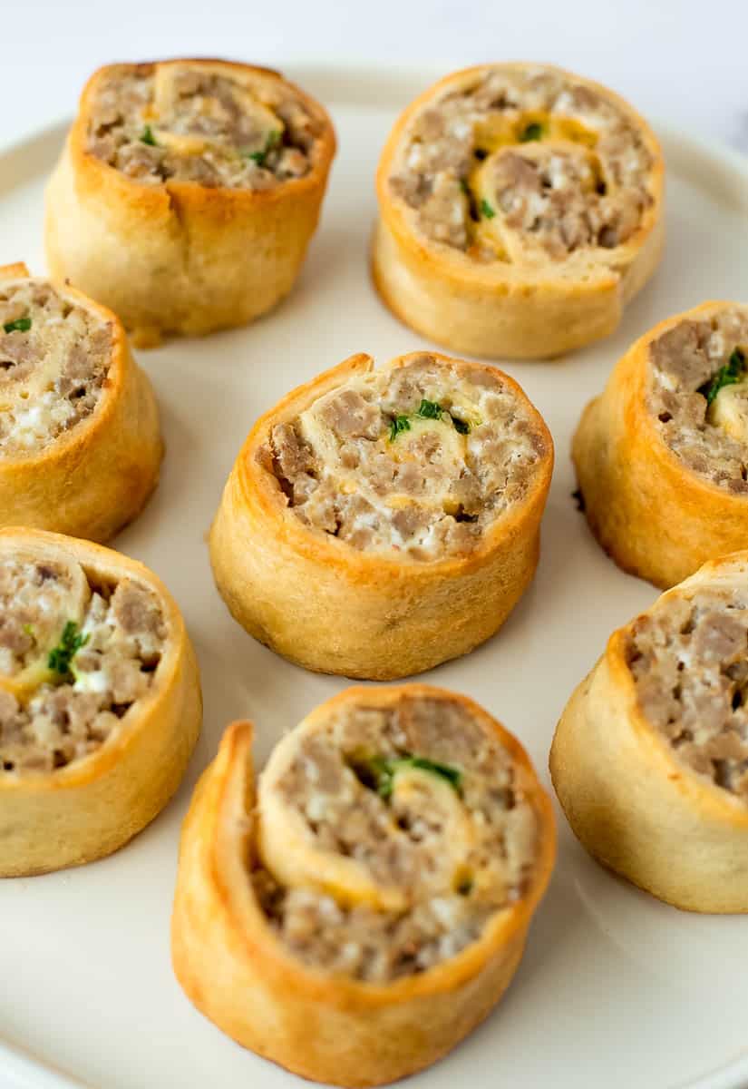Sausage pinwheels are shown on a white serving dish.
