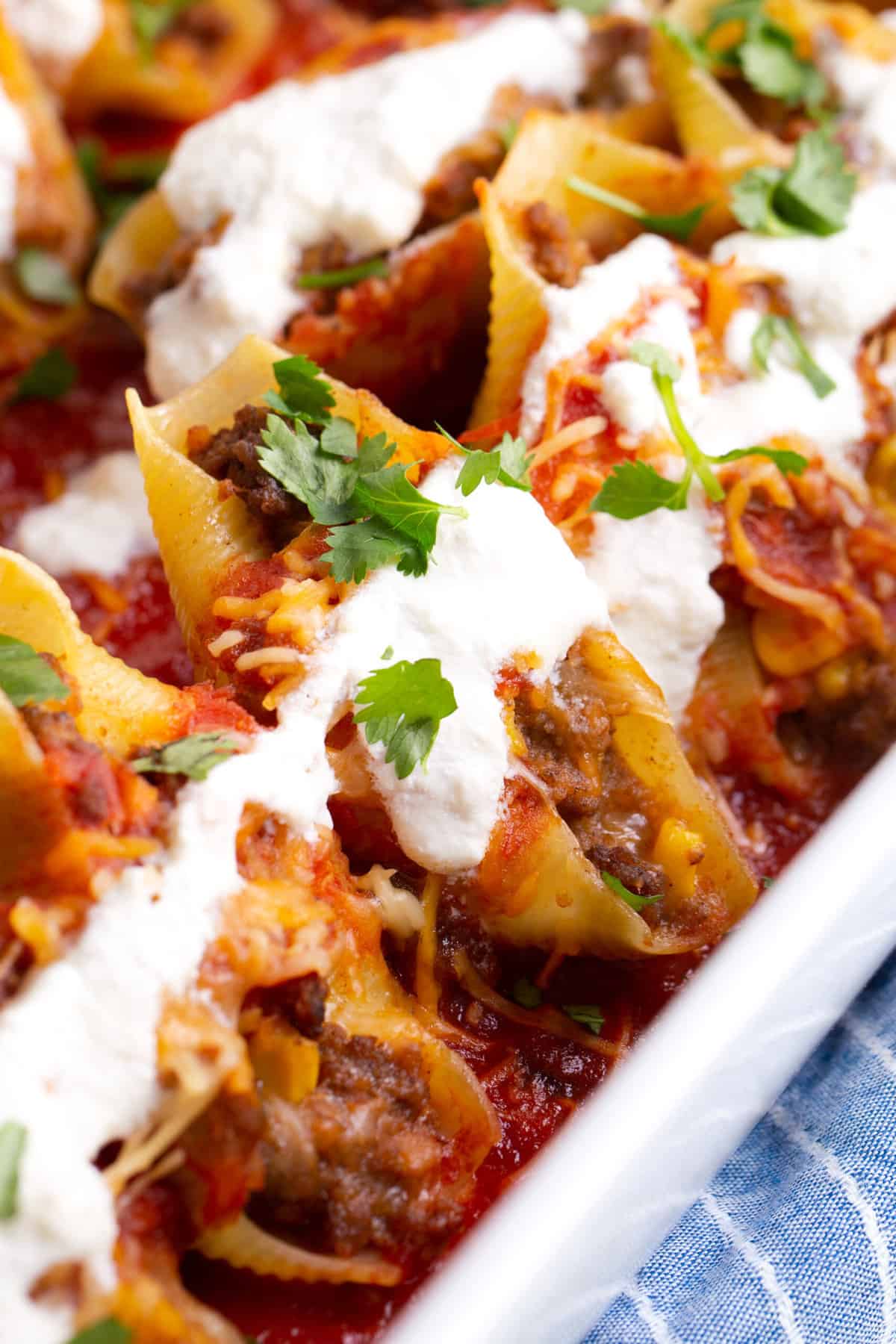 close up image of taco stuffed shells served in a large casserole dish.