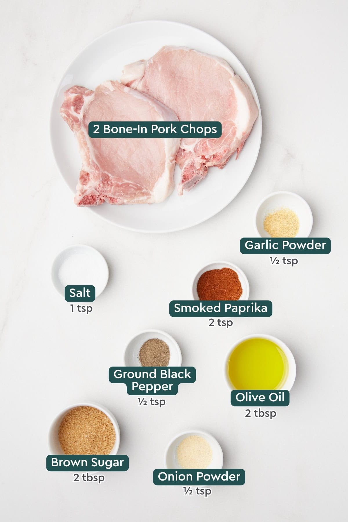 All of the ingredients for air fryer bone-in pork chops in bowls on a white countertop. 