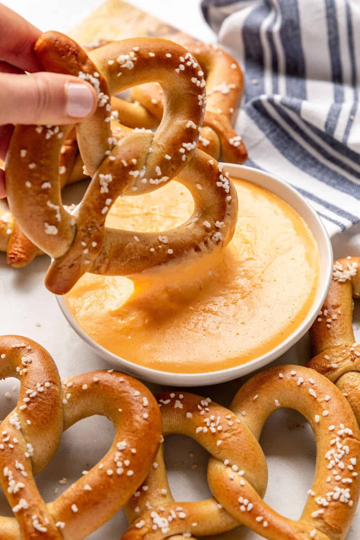 salted pretzel dipping into homemade cheese dip.