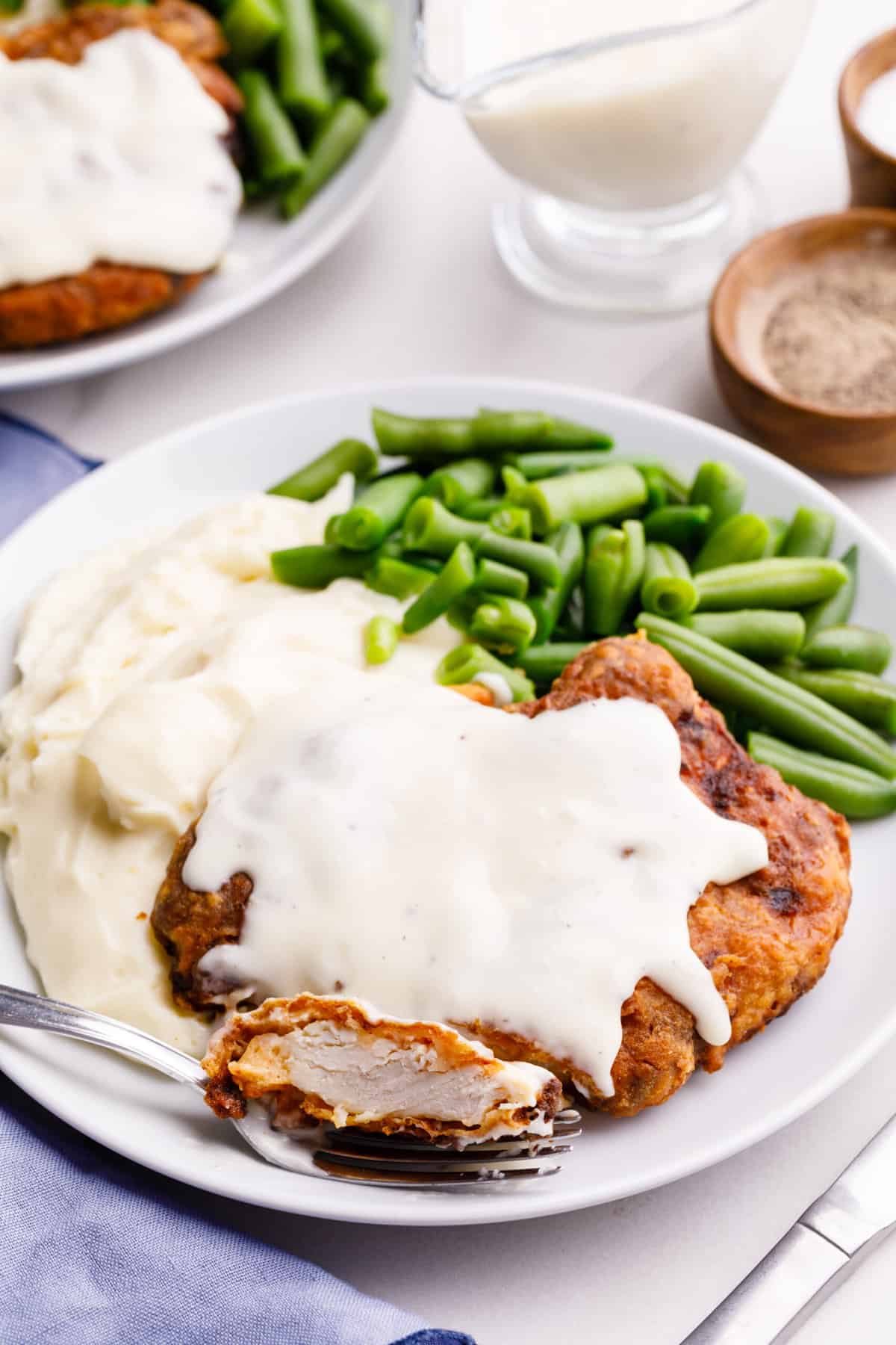plate of Air fryer chicken-fried steak with gravy and a side of mashed potatoes and green beans.