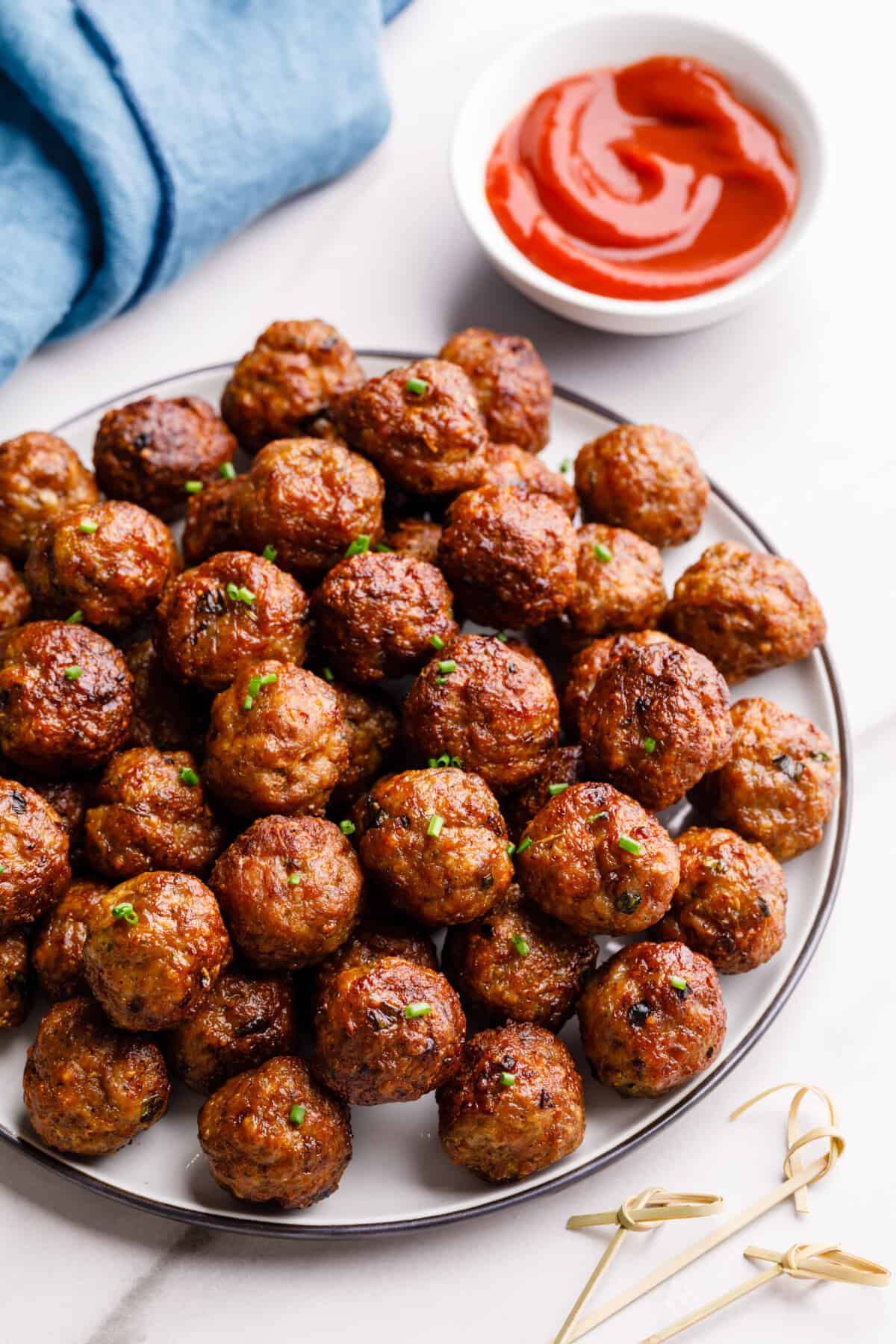 A plate of air fryer meatballs next to a bowl of dipping sauce.