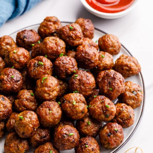 A plate of air fryer meatballs next to a bowl of dipping sauce.