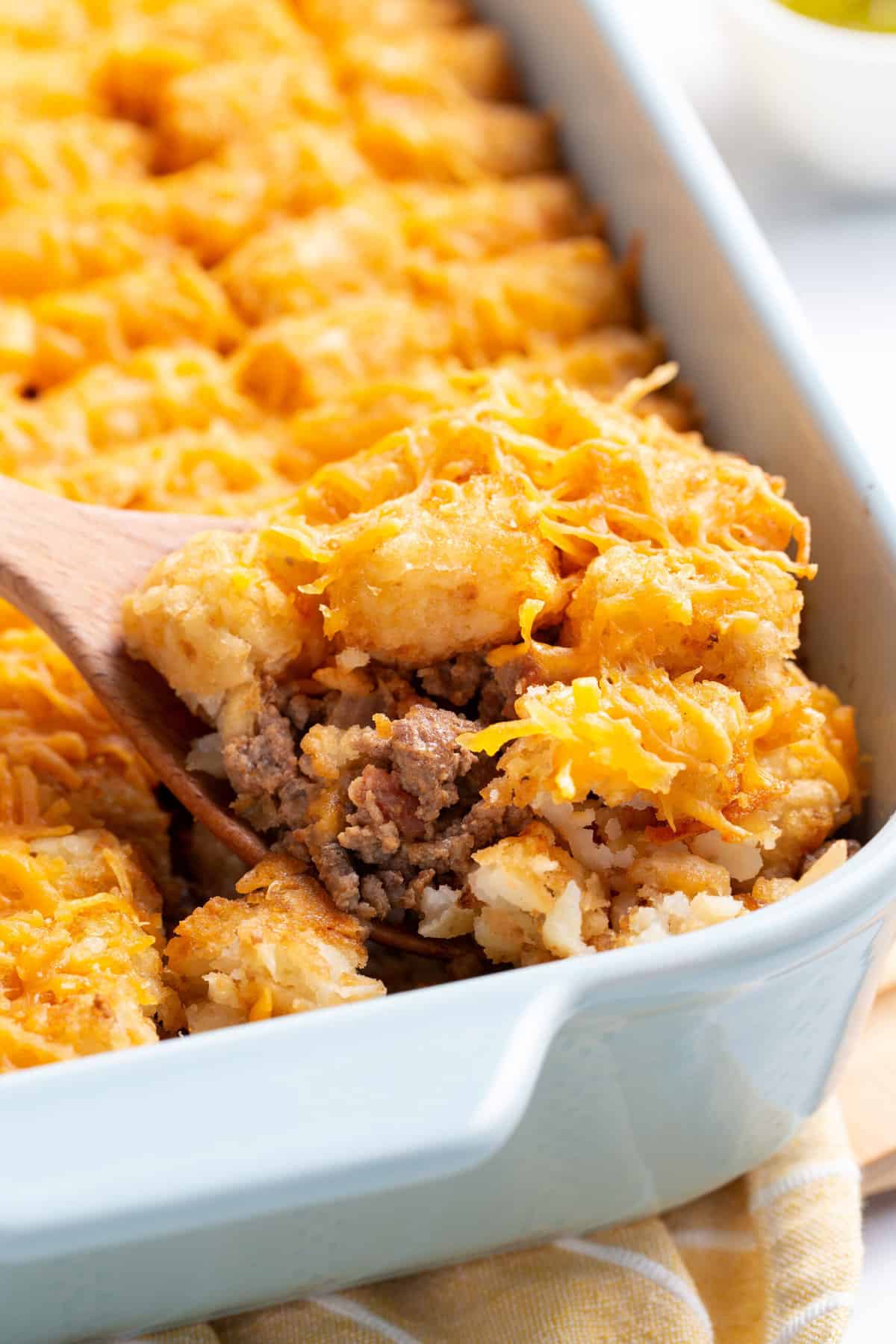wooden spoonful digging into a cheeseburger tater tot casserole.