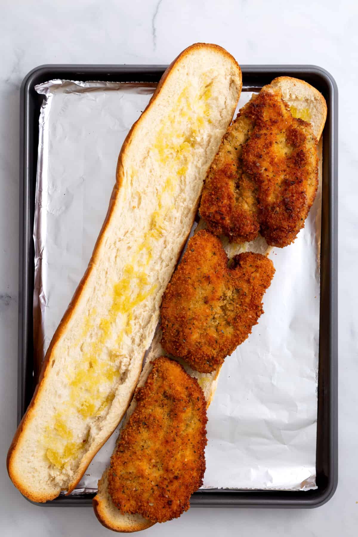 step 6 to make chicken parmesan sandwiches, French baguette with fried chicken fillets on the bread.