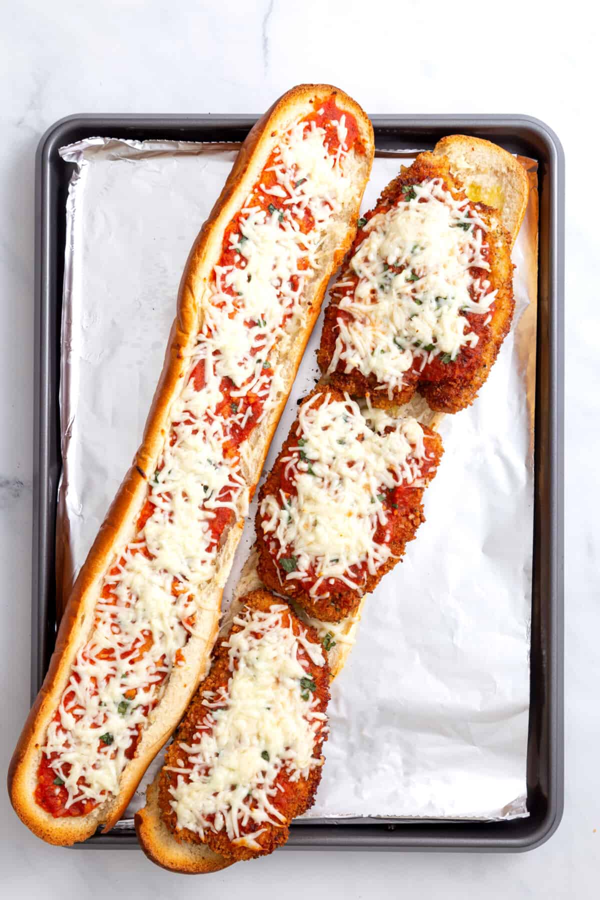 step 8 to make chicken parmesan sandwiches, French baguette with fried chicken, marinara sauce and mozzarella cheese.