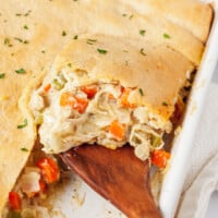 Chicken pot pie with crescent rolls being lifted from a baking dish.