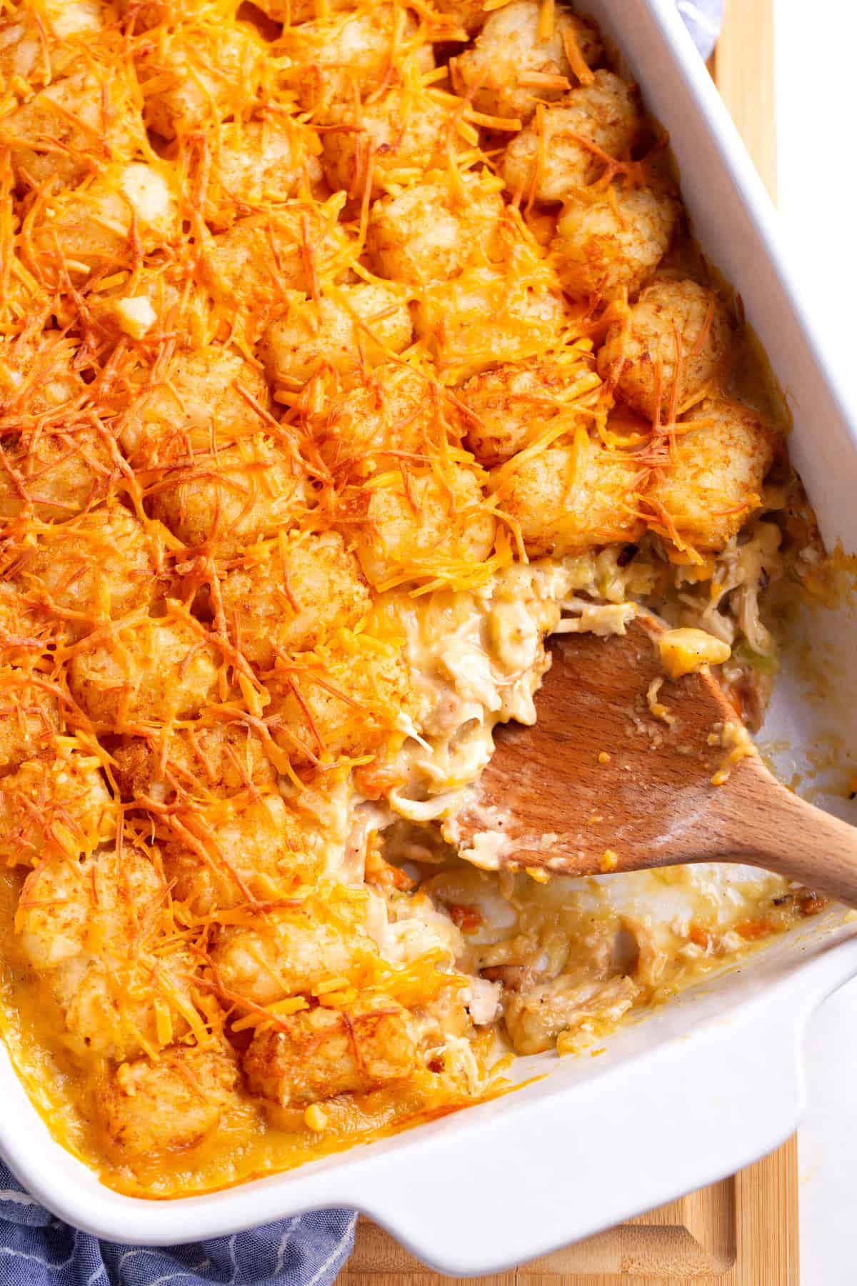 top down image of chicken tater tot casserole with a wooden spoon.