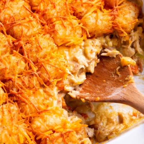 Chicken tater tot casserole being scooped with a wooden spoon.