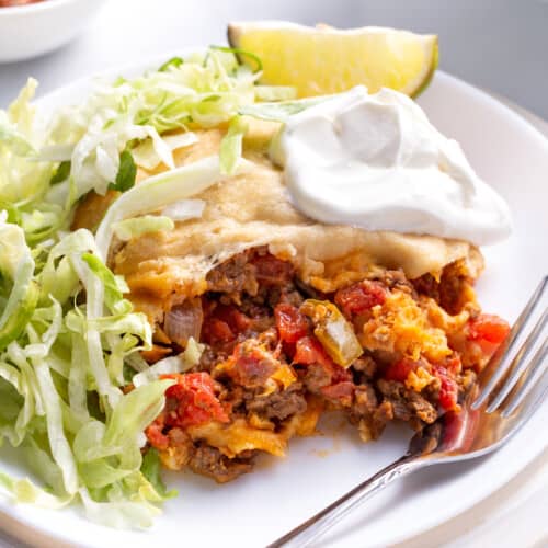 Crescent roll taco bake with lettuce and sour cream on a plate.