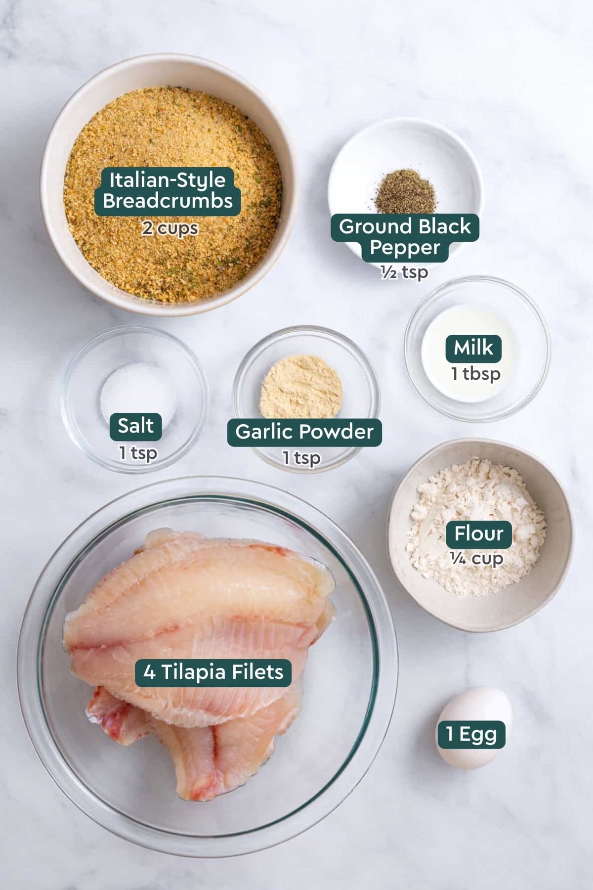 Ingredients for air fryer tilapia, including breadcrumbs, salt, pepper, garlic powder, flour, egg, milk, and tilapia.
