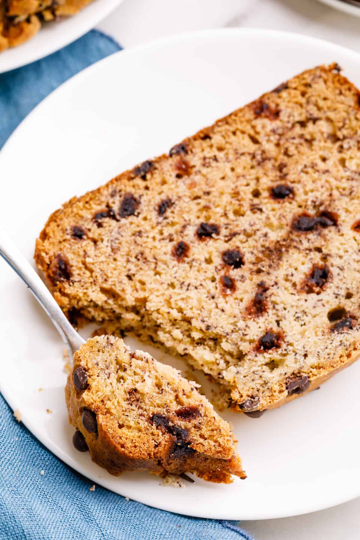 close up image of a slice of cake mix banana cake and a forkful of the bread served on a white round plate