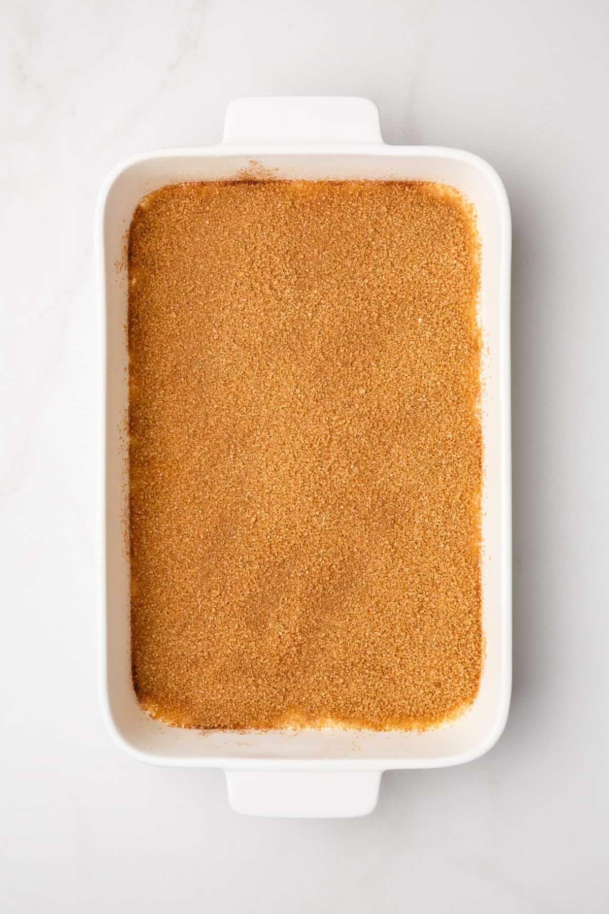 step 2 to make honey bun cake, sprinkle cinnamon sugar mix over the first layer of the cake