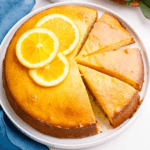 An orange cake with three slices cut.