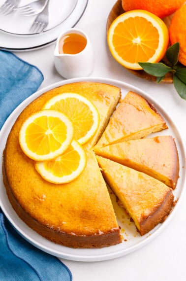 An orange cake with three pieces sliced.
