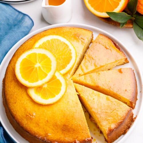 An orange cake with three pieces sliced.
