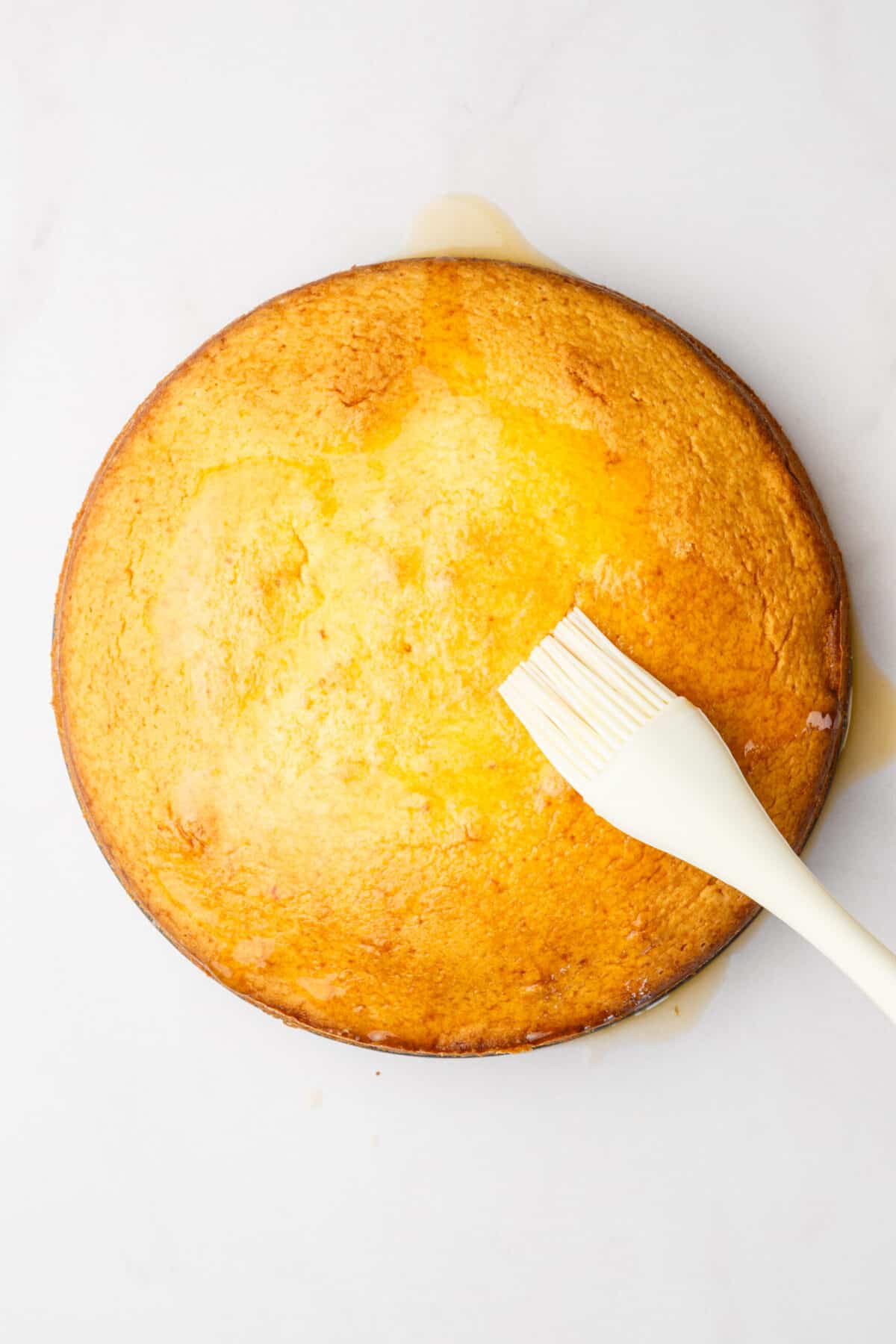 step 6 to make orange cake, use a kitchen brush to drench the orange glaze over the baked orange cake.