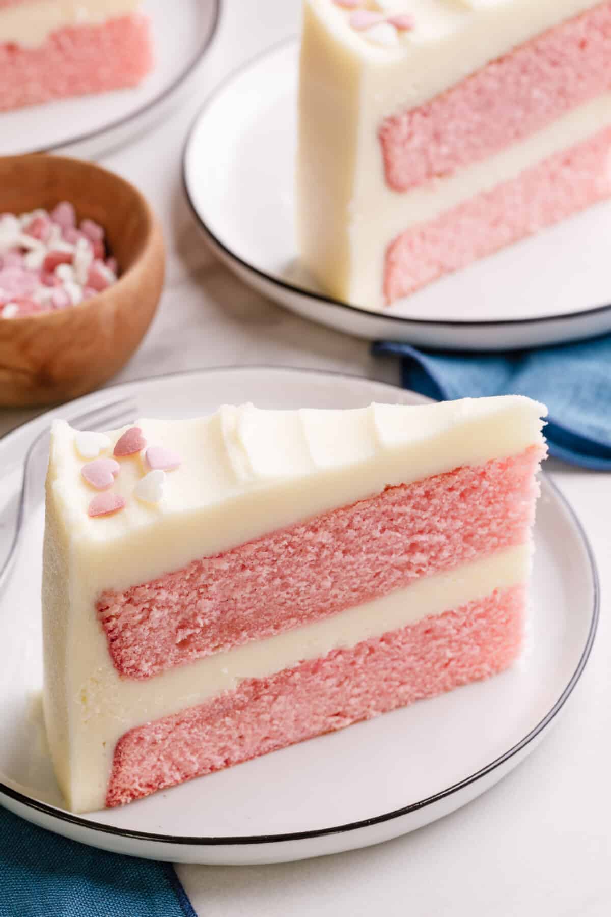 A slice of double layer pink velvet cake with buttercream frosting.
