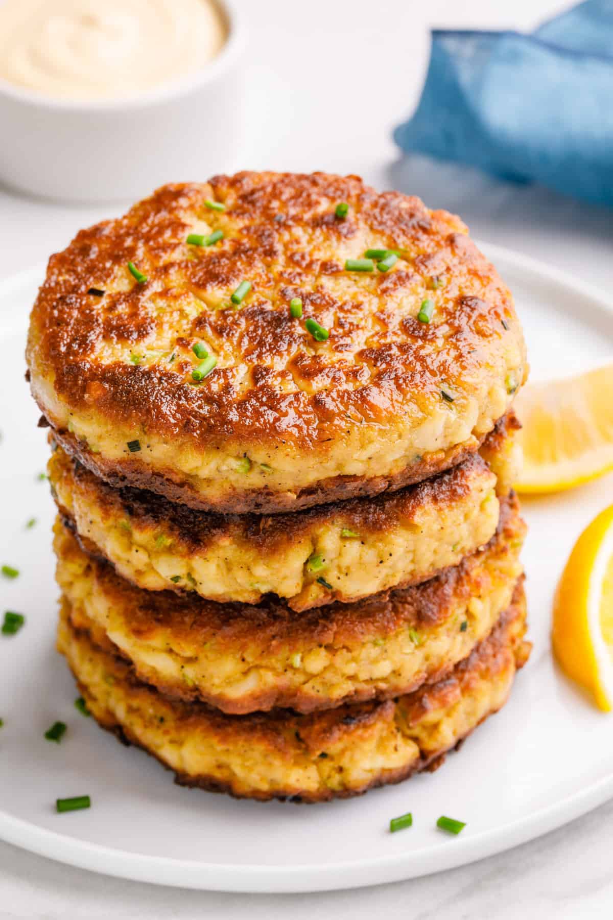 stack of four cooked crab cakes served on a white round plate