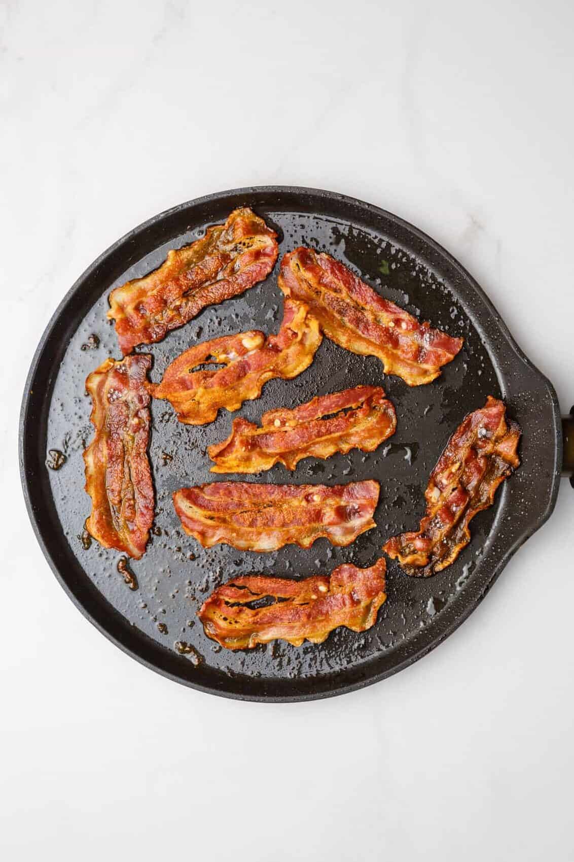 step 1 to make bacon pancakes, cook bacon on a cast iron skillet