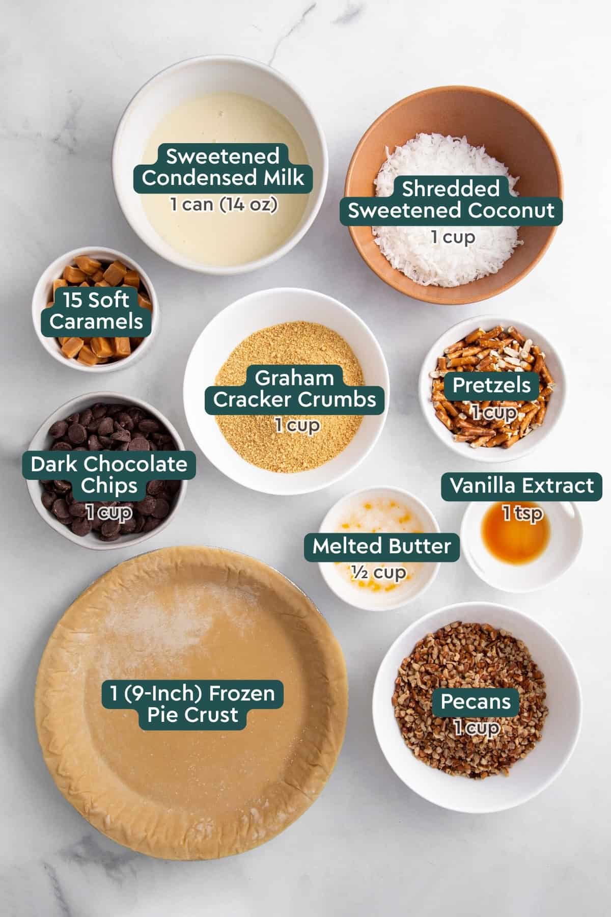 Ingredients for Texas trash pie, including condensed milk, coconut, caramels, graham cracker crumbs, pretzels, vanilla, butter, chocolate chips, pecans, pie crust.