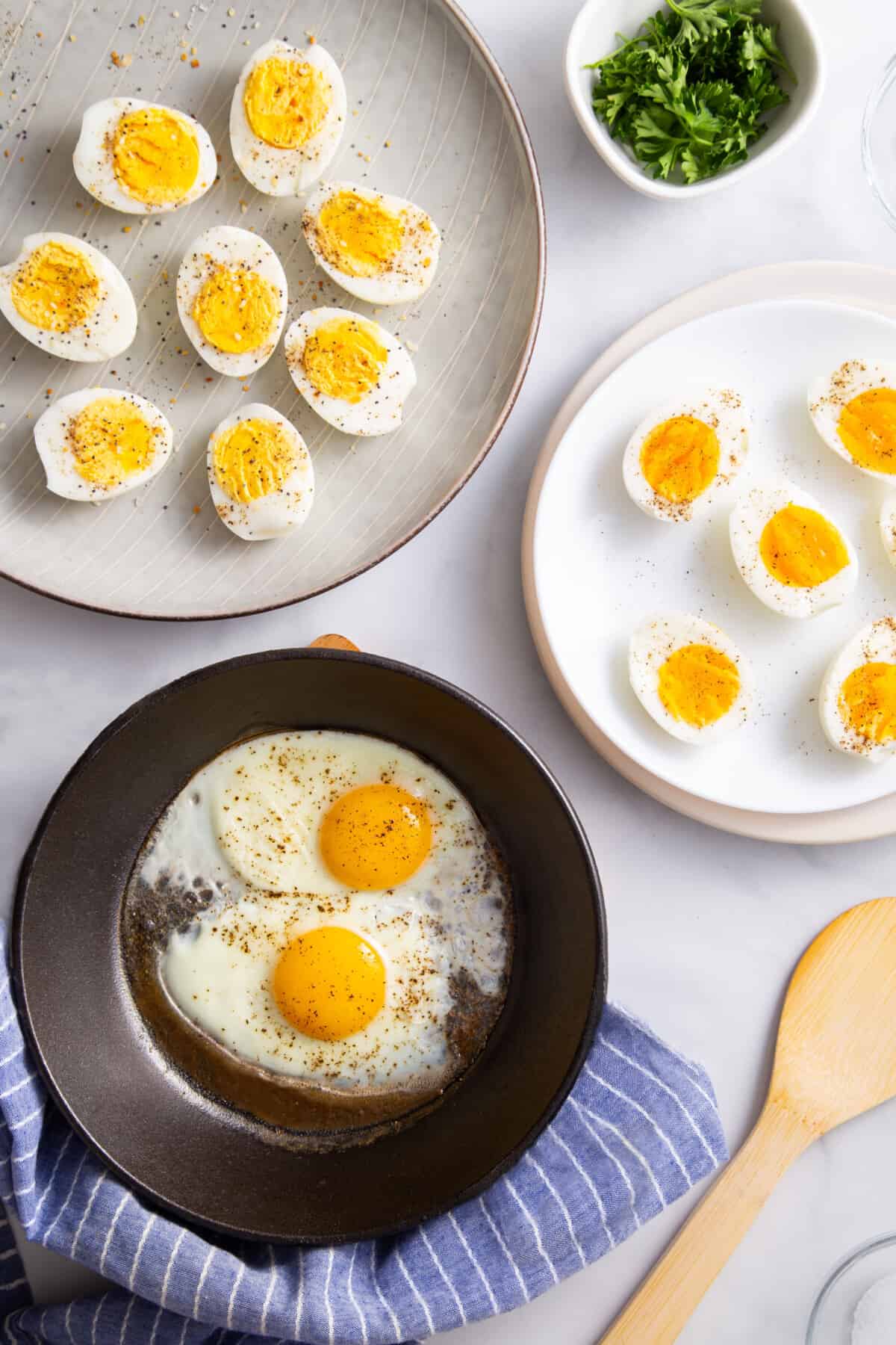 Plates of hard boiled eggs, soft boiled eggs, and fried eggs made in the air fryer.