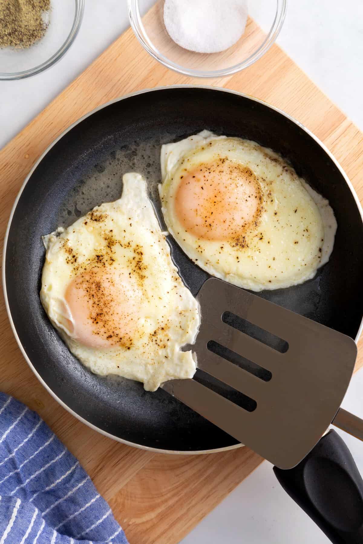 top down image of two basted eggs sitting in a skillet pan