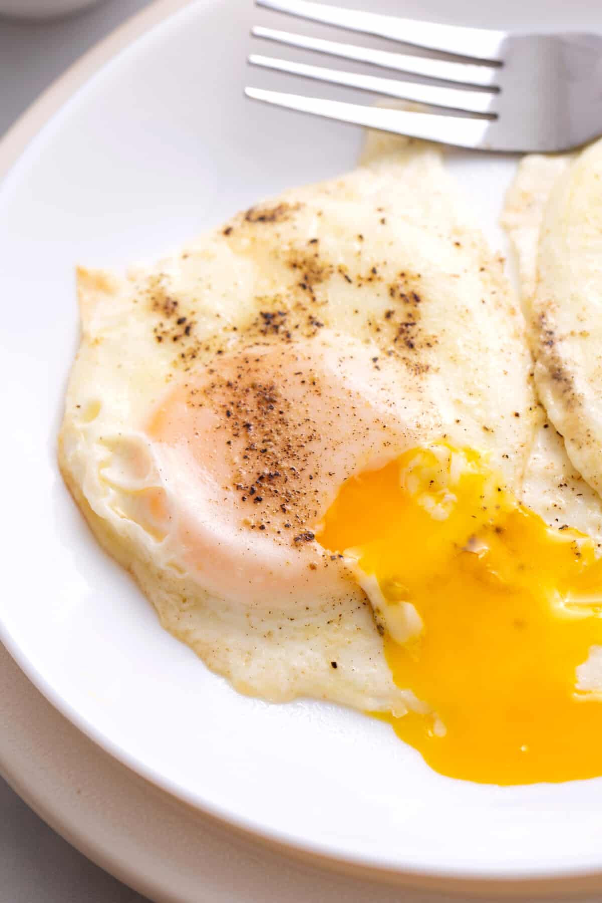 Two basted eggs on a plate with the yolk running.
