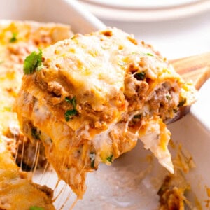 A serving of burrito casserole being lifted from a baking dish.